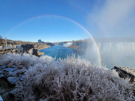 Photo for A beautiful view of Niagara Falls covered with ice, on a cold winter day, with a rainbow over the frosty grass - Royalty Free Image