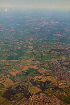 Foto de Una toma aérea vertical de campos verdes, edificios y carreteras durante el día desde un avión - Imagen libre de derechos