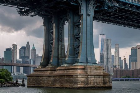 Téléchargez les photos : Un plan en angle bas de la base du Brooklyn Bridge, à New York, avec un paysage urbain en arrière-plan - en image libre de droit