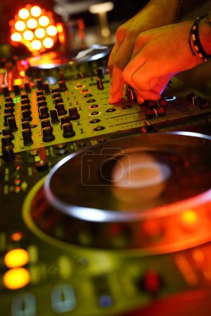 Photo for A vertical shot of a DJ turntable mixing board for electronic music and the hands of a DJ - Royalty Free Image