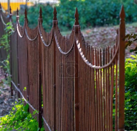 Photo for A closeup of brown iron fence with sharp points in the garden - Royalty Free Image