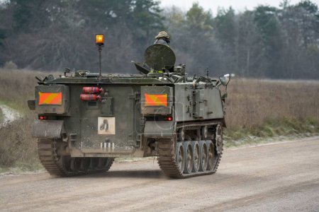 Photo for A army tracked personnel carrier driving an unmade road during the day - Royalty Free Image
