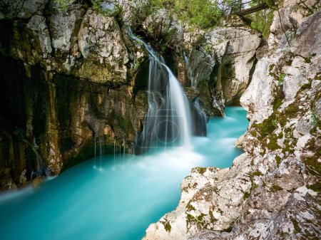 Foto de Hermosa cascada de larga exposición en el Gran Desfiladero de Soca en Eslovenia rodeado de rocas musgosas - Imagen libre de derechos