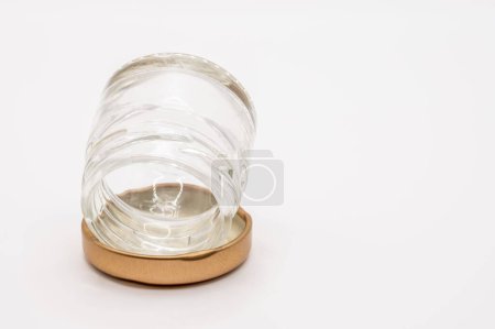 Téléchargez les photos : Gros plan d'un petit pot de confiture vide en verre transparent avec un couvercle métallique vissé de couleur bronze - en image libre de droit