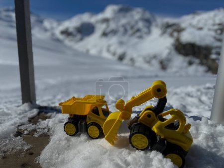 Téléchargez les photos : Les camions-jouets et les pelles dans la neige d'hiver en face d'une montagne enneigée dans les Alpes suisses - en image libre de droit