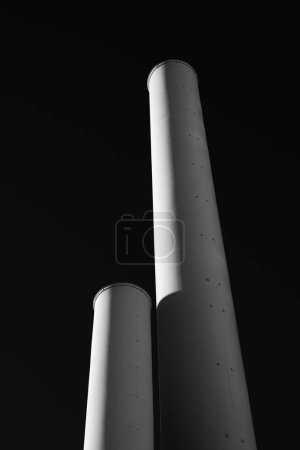 Photo for A grayscale vertical shot of two long pipes against black background - Royalty Free Image