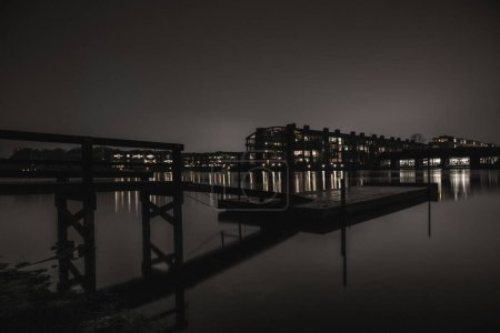 Téléchargez les photos : Le pont sur l'eau avec des bâtiments en arrière-plan la nuit - en image libre de droit