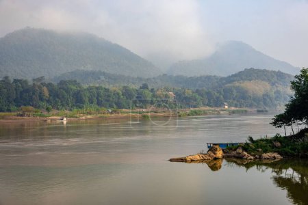 Téléchargez les photos : Un beau cliché du Mékong avec un bateau flottant près des montagnes à Luang Prabang, Laos - en image libre de droit