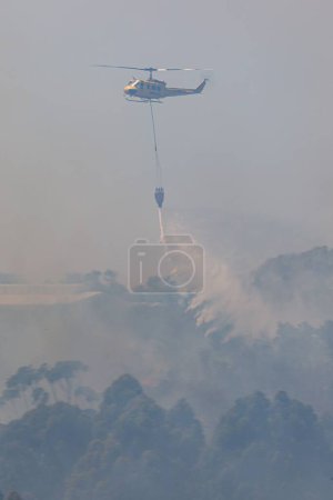 Foto de Un disparo vertical de un helicóptero huey dejando caer una bolsa de agua en llamas - Imagen libre de derechos