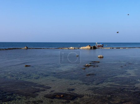 Foto de Una vista panorámica de un barco navegando a lo largo de la costa de una playa en un día soleado - Imagen libre de derechos