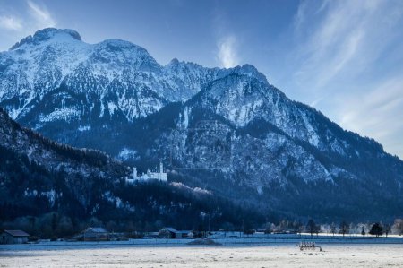 Foto de Una hermosa vista del castillo en Schwangau, Alemania bajo una enorme montaña nevada - Imagen libre de derechos