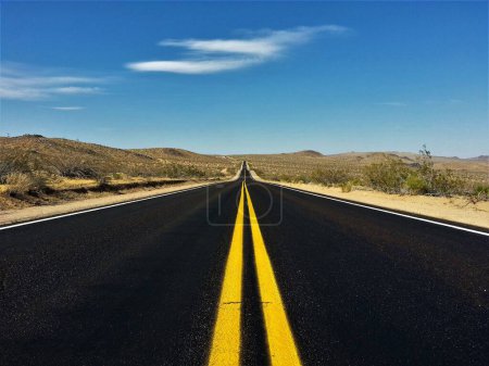 Photo for A black asphalt country road with strong yellow lines in the middle of the road. - Royalty Free Image