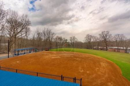 Photo for View of typical nondescript high school softball field with clay infield from first base side of field looking toward second base. No people visible. - Royalty Free Image