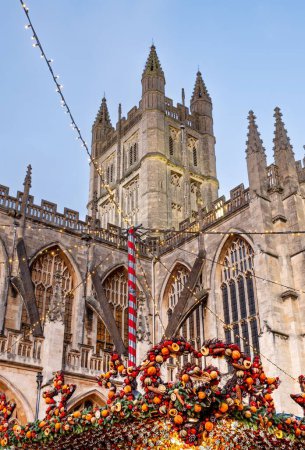 A vertical low-angle view of Christmas decoration and lights hung before the Bath Abbey