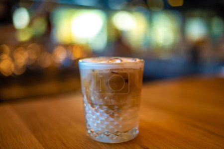 Téléchargez les photos : Un café latte glacé dans un verre de cristal une table de bar en bois - en image libre de droit