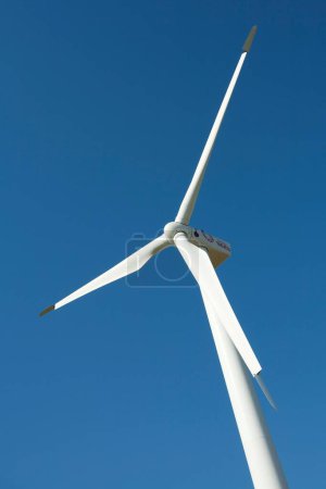 Foto de Un disparo vertical de una turbina de energía eólica en una colina con un fondo azul del cielo - Imagen libre de derechos