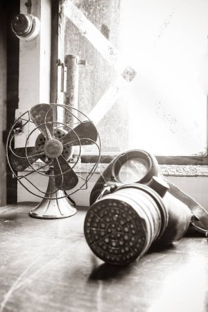Téléchargez les photos : Plan vertical d'un ventilateur électrique vintage et d'un masque à gaz de la Seconde Guerre mondiale posé sur un bureau à Wartime In The Vale - en image libre de droit