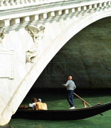 Foto de Una góndola turística que pasa por debajo de un puente sobre el canal en Venecia, Italia - Imagen libre de derechos