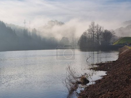 Photo for The scenic view of a lake before the trees covered in steam - Royalty Free Image