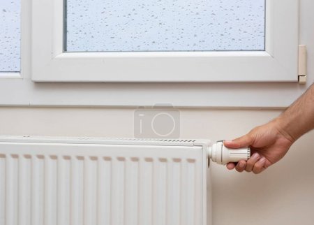 Foto de La mano de un hombre ajustando la temperatura de un radiador - Imagen libre de derechos