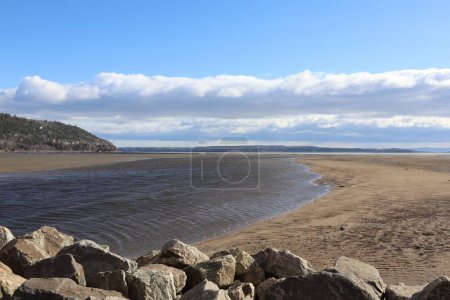 Photo for A scenic view of rocks on the sandy beach and seashore during low tide under blue cloudy sky - Royalty Free Image