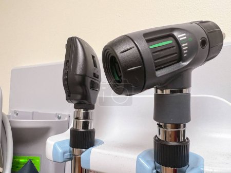 Téléchargez les photos : Gros plan d'un ophtalmoscope noir sur le mur d'un cabinet de médecin - en image libre de droit