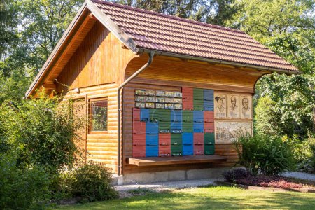 Téléchargez les photos : Une jolie maison d'abeilles en bois avec une cour verte avec des pins à Mozirje, Slovénie - en image libre de droit