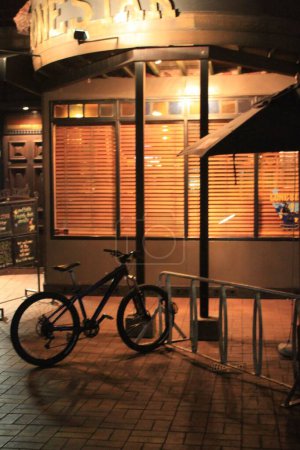 Foto de Una vista vertical nocturna del exterior de una tienda y una bicicleta estacionada, en la calle Queenstown en Nueva Zelanda - Imagen libre de derechos