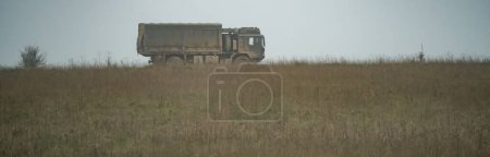 Téléchargez les photos : Le camion militaire se déplaçant dans un champ - en image libre de droit