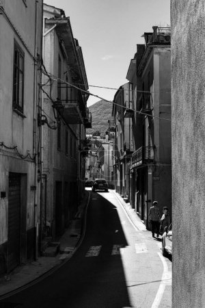 A vertical grayscale of a narrow street in the town and commune of Lauria in southern Italy