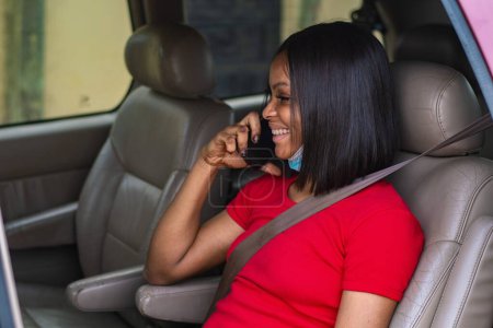 Foto de Bastante africana dama haciendo una llamada telefónica en un coche - Imagen libre de derechos