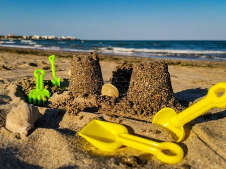 Foto de Un primer plano de herramientas de playa y castillo de arena con conchas en la playa - Imagen libre de derechos