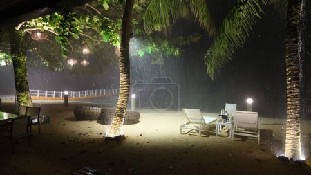 Foto de Una lluvia cayendo en un destino de vacaciones con palmeras y sillas plegables - Imagen libre de derechos