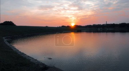 Téléchargez les photos : Une belle vue sur un coucher de soleil avec des nuages colorés sur un lac calme - en image libre de droit