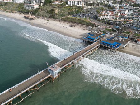 Photo for An aerial view over San Clemente Pier on sea waves with cityscape houses on the horizon - Royalty Free Image