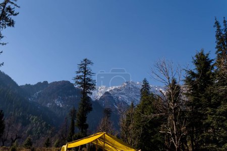 Téléchargez les photos : Vue panoramique d'hiver depuis la route asphaltée dans les montagnes couvertes de neige et d'arbres sur le côté de la route sur un fond de ciel bleu et de nuages - en image libre de droit