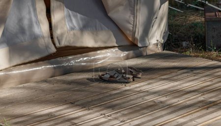 Téléchargez les photos : Une image de sandales sur un plancher de bois devant une tente de camping - en image libre de droit