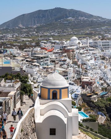 Foto de Una vertical de una hermosa iglesia contra el paisaje urbano densamente poblado de Fira en Santorini, Grecia - Imagen libre de derechos