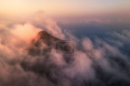 Téléchargez les photos : Une montagne au-dessus des nuages pendant un coucher de soleil - en image libre de droit