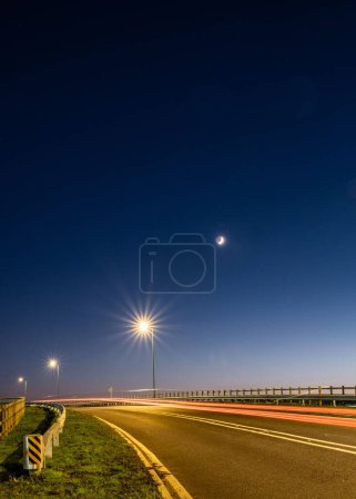 Foto de Una toma vertical de los senderos del semáforo en una carretera vacía con un cielo azul oscuro - Imagen libre de derechos