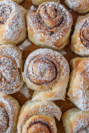 Photo for A vertical top closeup of tasty cinnamon buns on a wooden dock with sugar powder on them - Royalty Free Image