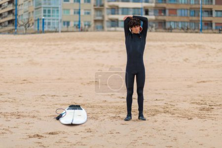 Téléchargez les photos : Un surfeur masculin caucasien se prépare à aller surfer dans l'océan - en image libre de droit
