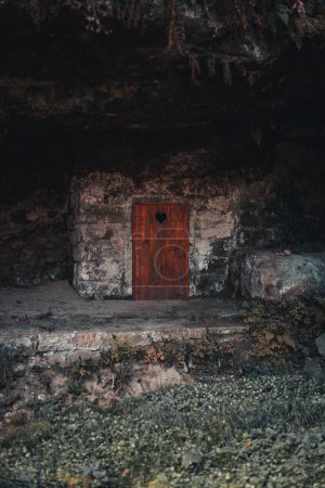 Foto de Un plano vertical del antiguo edificio de piedra con una vieja puerta vintage con un agujero en forma de corazón en las montañas sajonas de Suiza, Alemania - Imagen libre de derechos