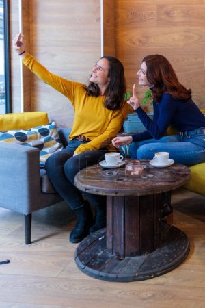 Photo for Two Caucasian women sitting in a cafe taking a selfie - Royalty Free Image