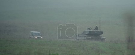 Photo for A military tank and soldiers with guns on a field - Royalty Free Image