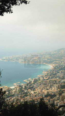 Téléchargez les photos : Gros plan vertical d'une ville sur la côte d'un océan par une journée brumeuse - en image libre de droit