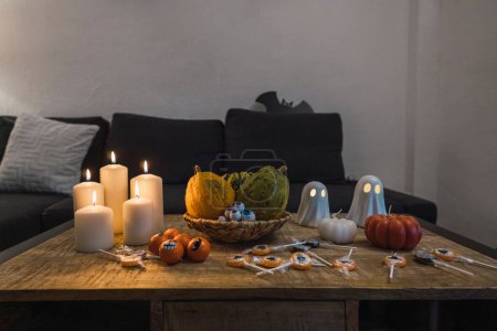 Foto de Las decoraciones de Halloween de tazas, velas, figuras fantasma y calabazas puestas sobre la mesa - Imagen libre de derechos
