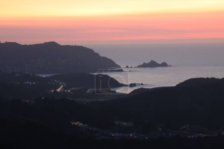 Téléchargez les photos : Silhouettes de collines sur le littoral avec un magnifique coucher de soleil rose en arrière-plan - en image libre de droit
