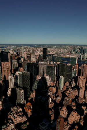 Téléchargez les photos : Un plan vertical au sommet de l'Empire State Building jetant son ombre sur les bâtiments de Manhattan. - en image libre de droit
