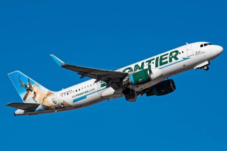 Téléchargez les photos : Un avion Frontier Airlines A320 N233FR volant dans un ciel bleu - en image libre de droit